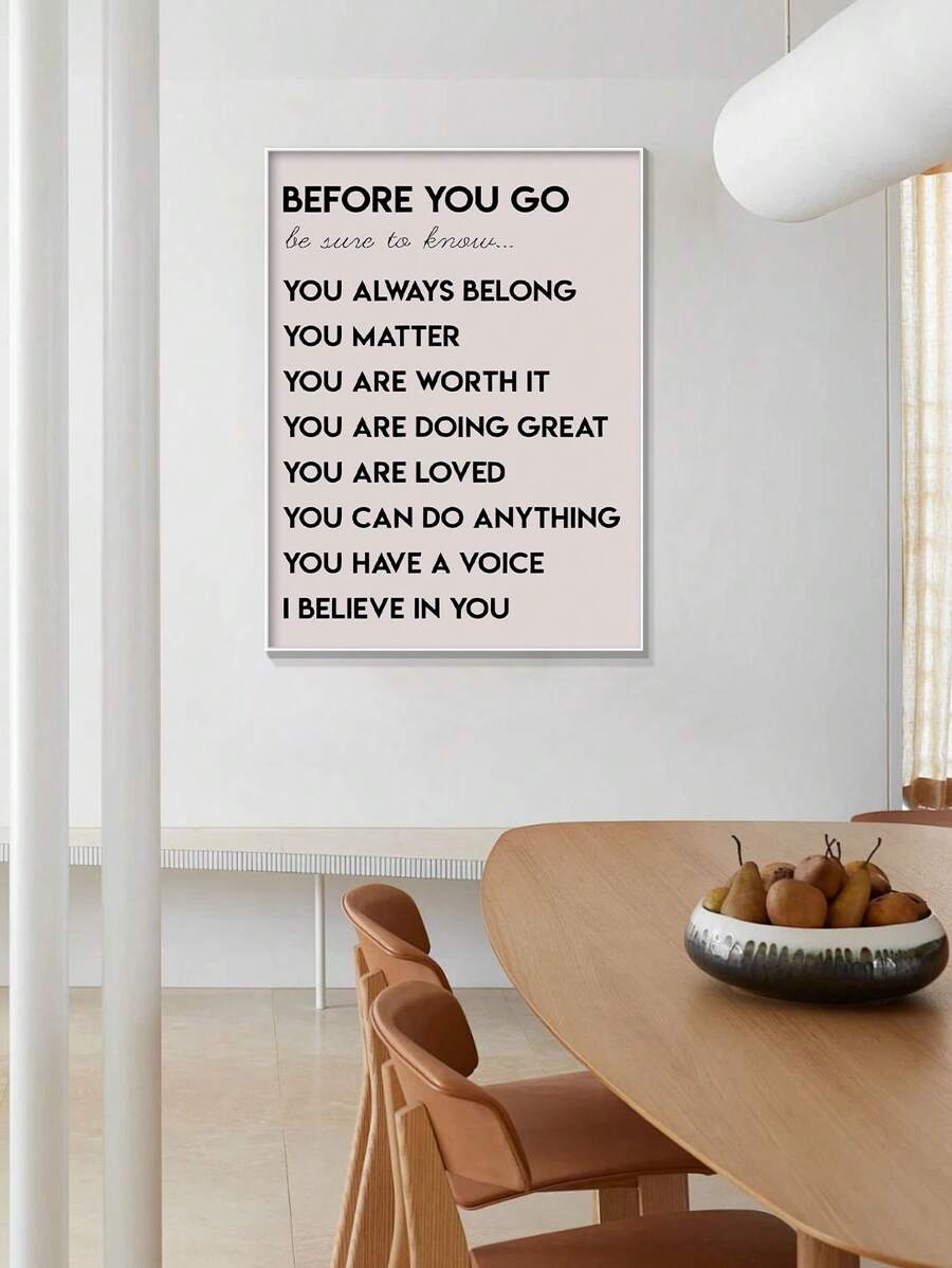 White framed Before You Go affirmation poster above a contemporary dining table