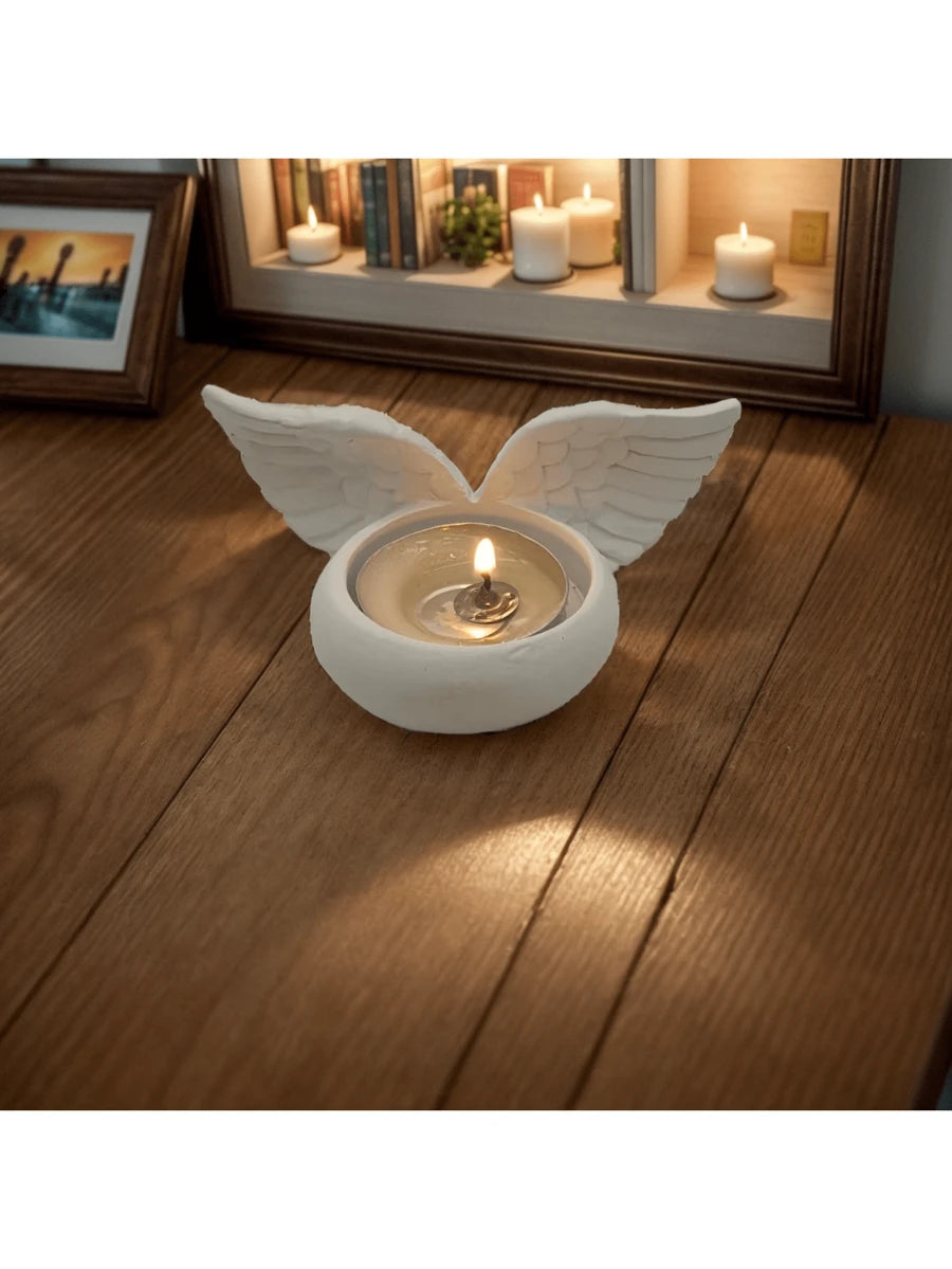White wing shaped candle holder with carved feather texture and warm tealight glow.
