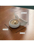 Angel wing tealight holder on wood table with white matte finish.