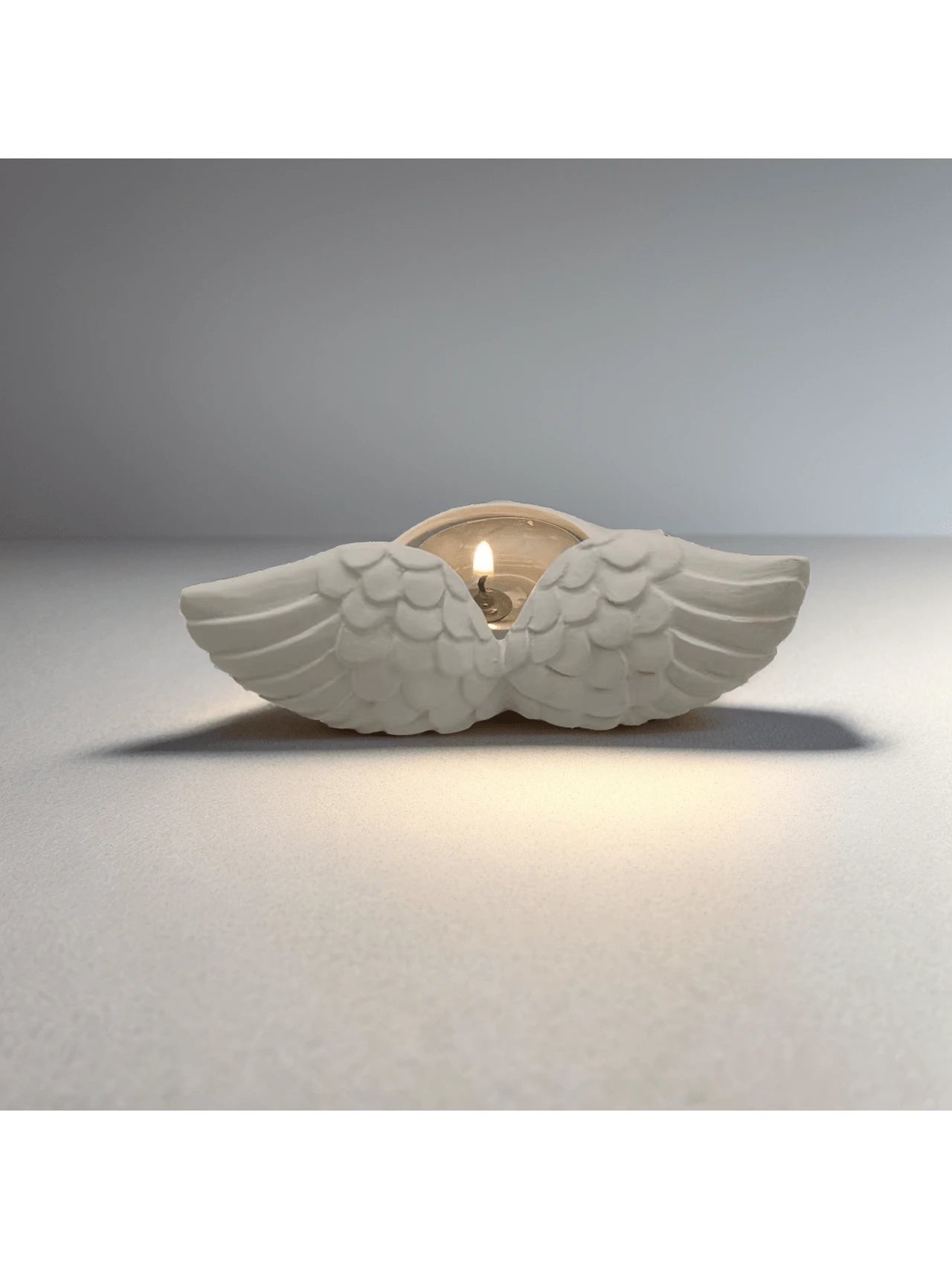 Wing candle decor displayed on shelf or window ledge for soft ambience.