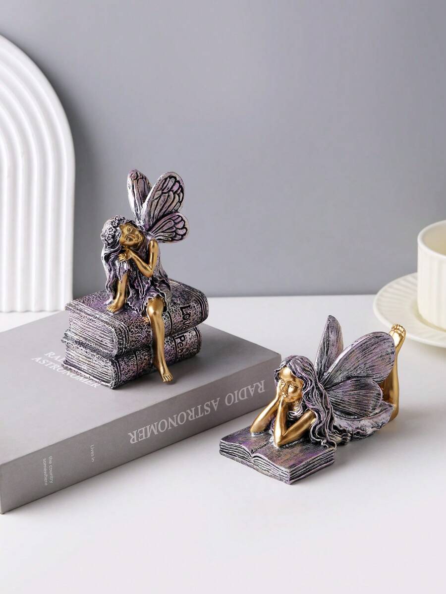Fairy figurine sitting on stacked books with long hair and detailed wings.