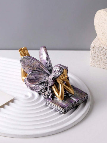 Resin book-shaped angel decor with fairy lying on open book.