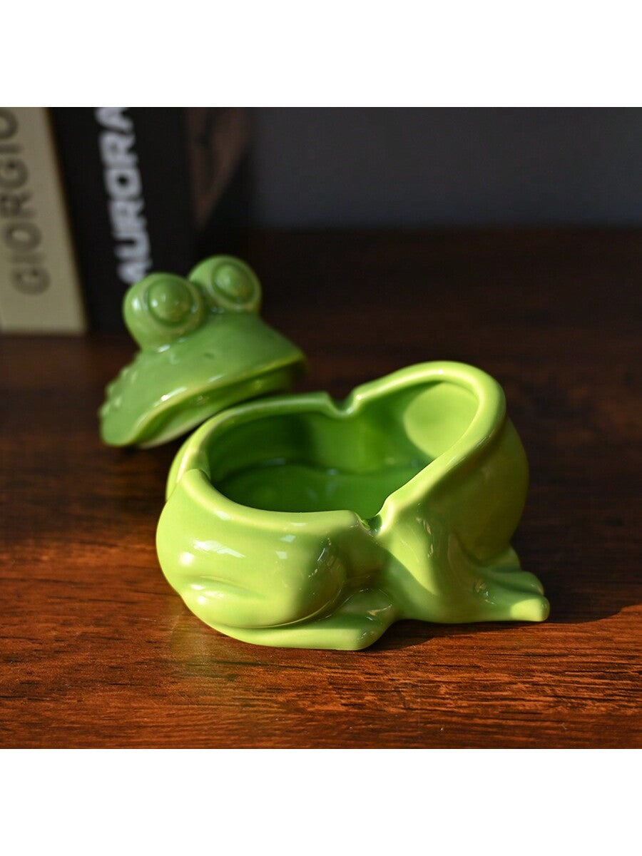 Add a touch of whimsy to your home or office with this unique and asymmetrical ceramic ashtray featuring a playful frog design. With its lid, it not only provides a functional way to dispose of ash and debris, but also acts as a decorative piece. Made with expert craftsmanship, this ashtray is sure to impress.