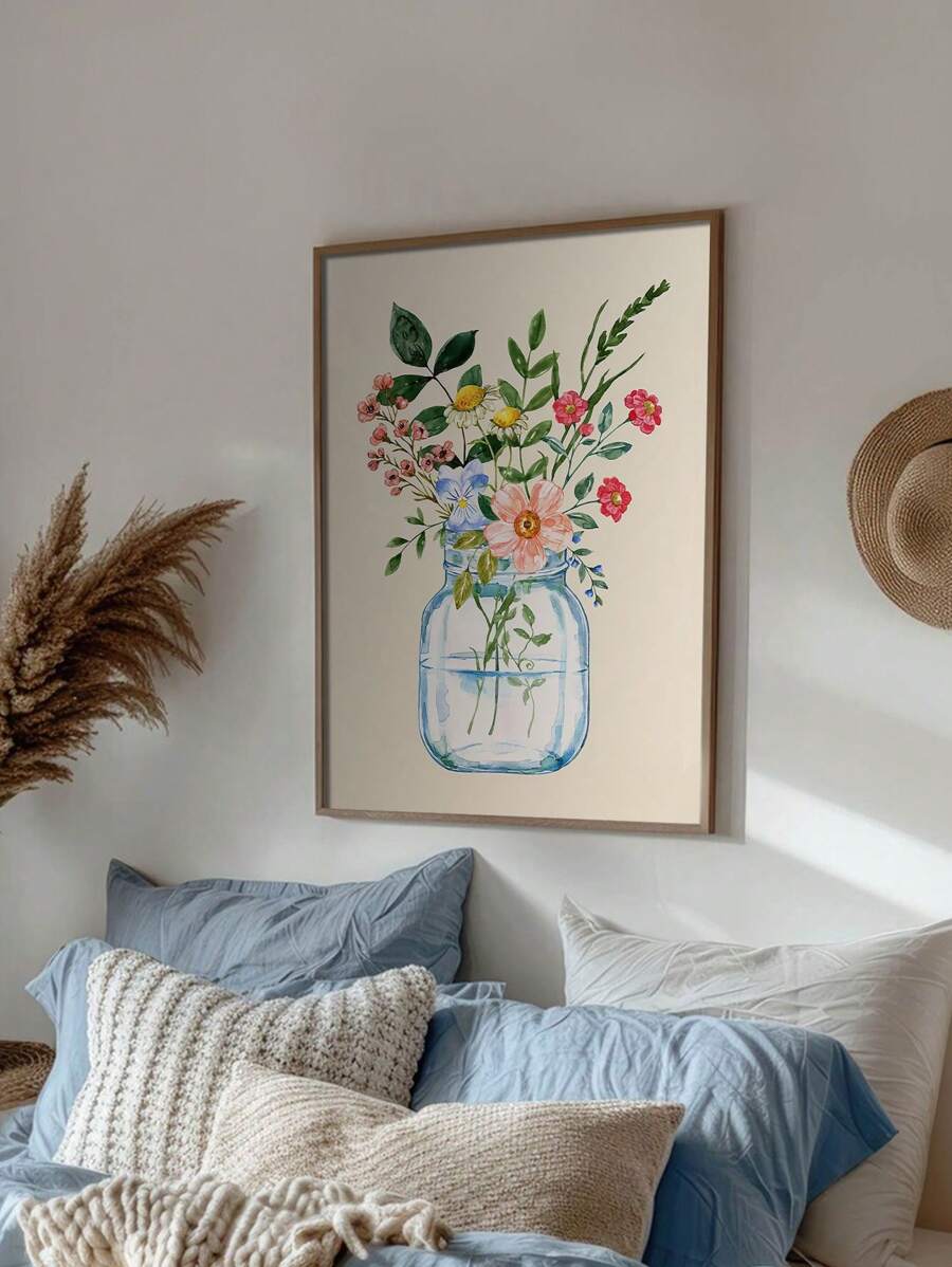 Framed watercolor bouquet in a blue glass jar above layered blue bedding