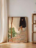 White framed girl with books print displayed beside a leafy vase