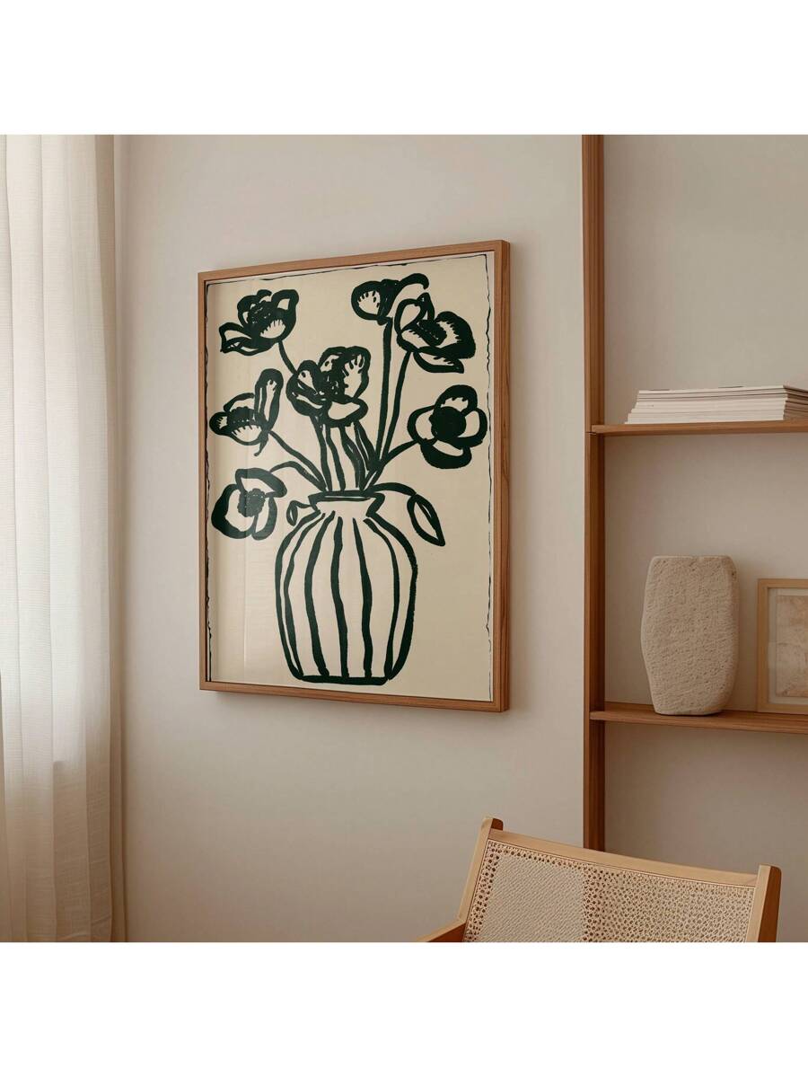 Framed dark green flower vase print hanging beside wood shelving and cane chair
