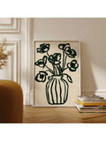 Framed dark green flower vase line art leaning near books in warm neutral room