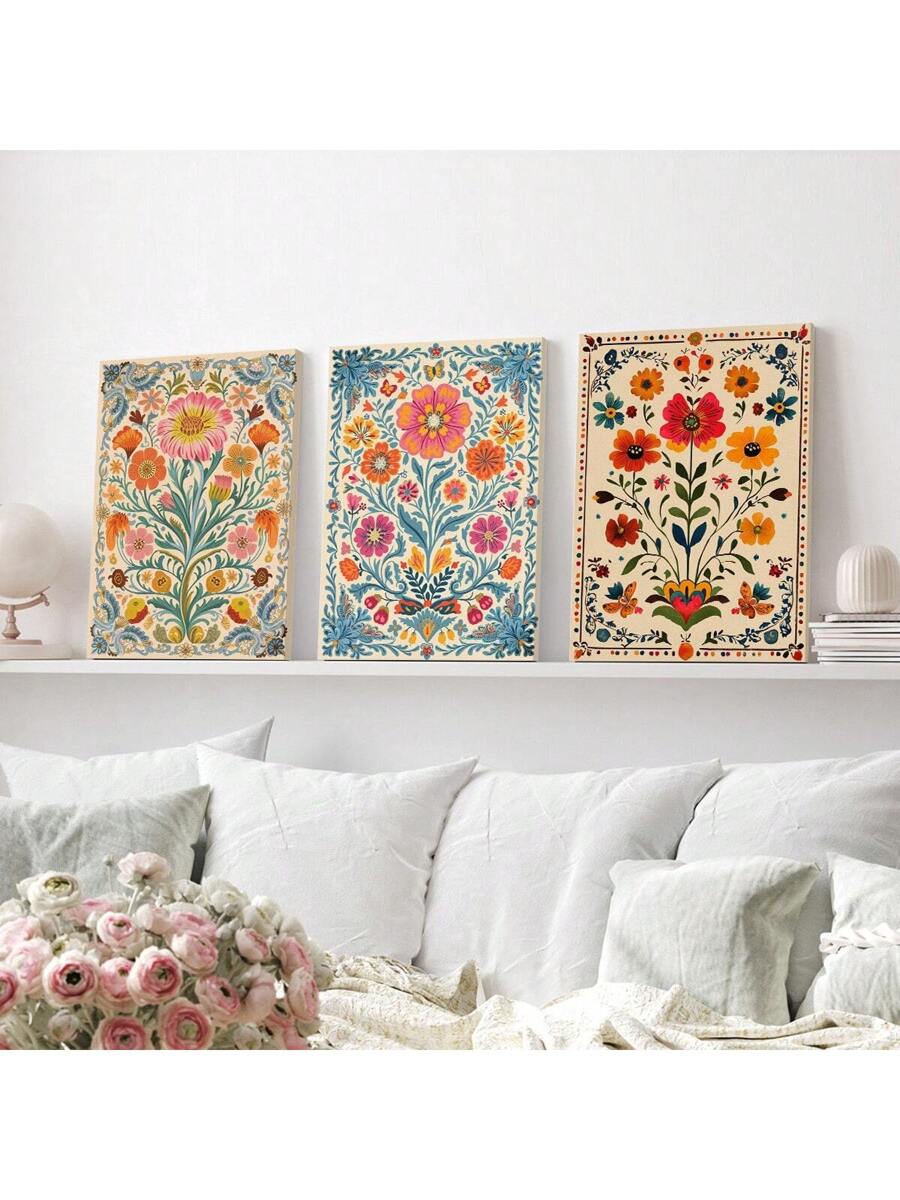 Three ornate folk floral canvas prints displayed on white shelf above white sofa with colorful botanical patterns