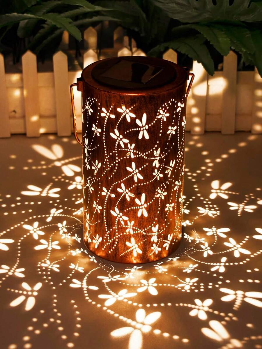 Solar bronze dragonfly lantern glowing warm yellow on outdoor table.