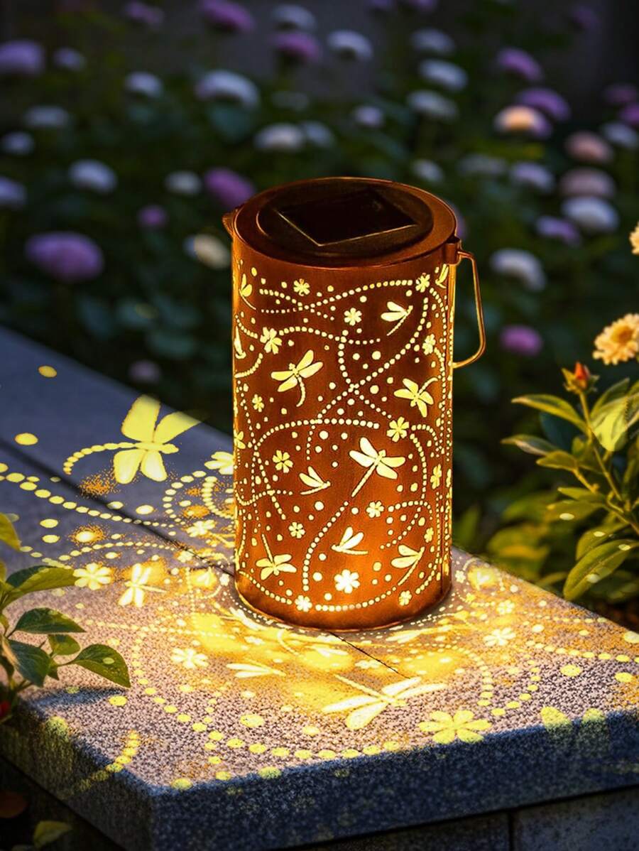 Solar bronze dragonfly lantern glowing warm yellow on outdoor table.