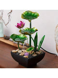 Green and gold lotus fountain flowing on wooden table with pink flower and cord.