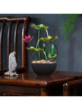Running tabletop lotus fountain beside stone figurine on wooden furniture.