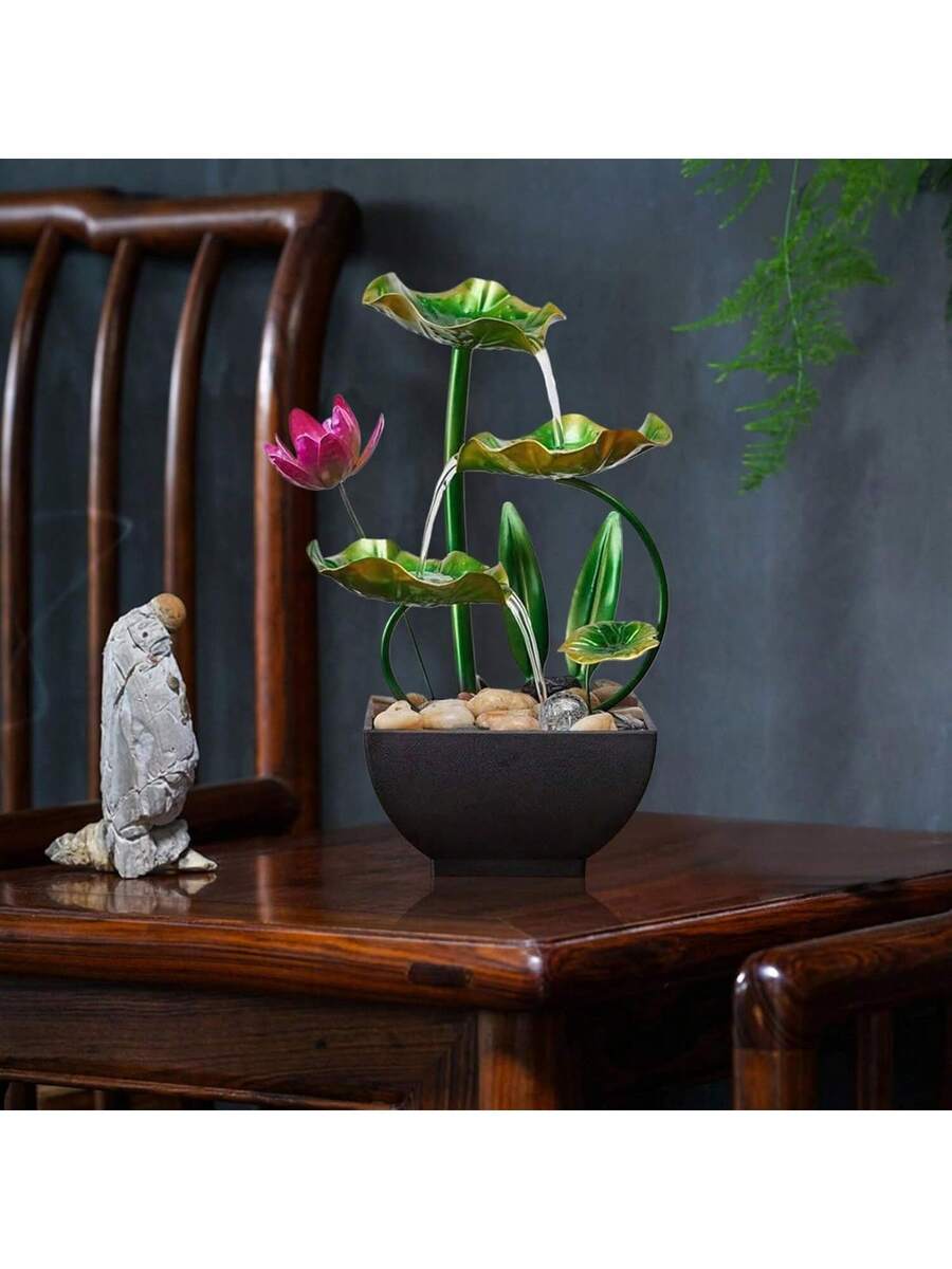 Running tabletop lotus fountain beside stone figurine on wooden furniture.