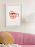 Pink floral cafecito poster in a white frame above a pink sofa