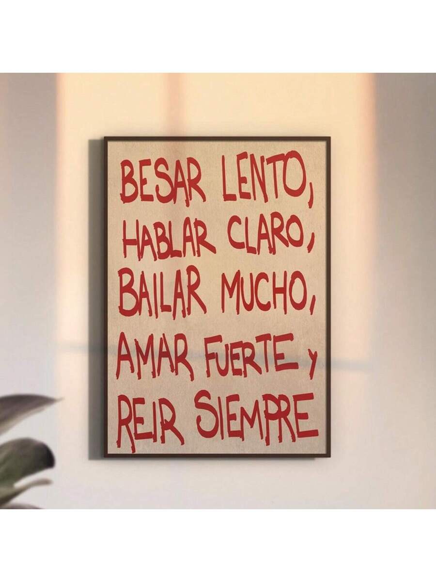 Black framed Spanish quote artwork on a softly lit wall beside large plant leaves