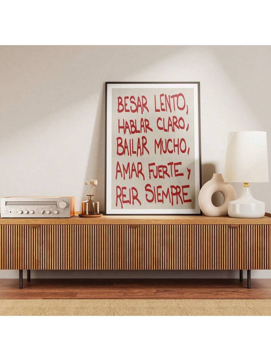 Red lettered Spanish quote print on a mid-century credenza beside a radio and ceramic lamps
