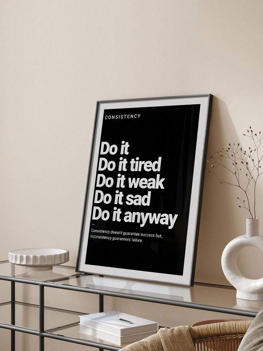Framed consistency quote poster on glass console with white sculptural vase