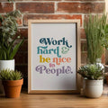 Inspirational quote wall art in a wood frame beside green plants