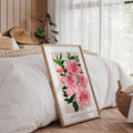 Light-wood framed pink azalea floral print leaning beside a bright white bed