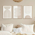 Framed three-panel abstract line art displayed above layered neutral bedding and pillows