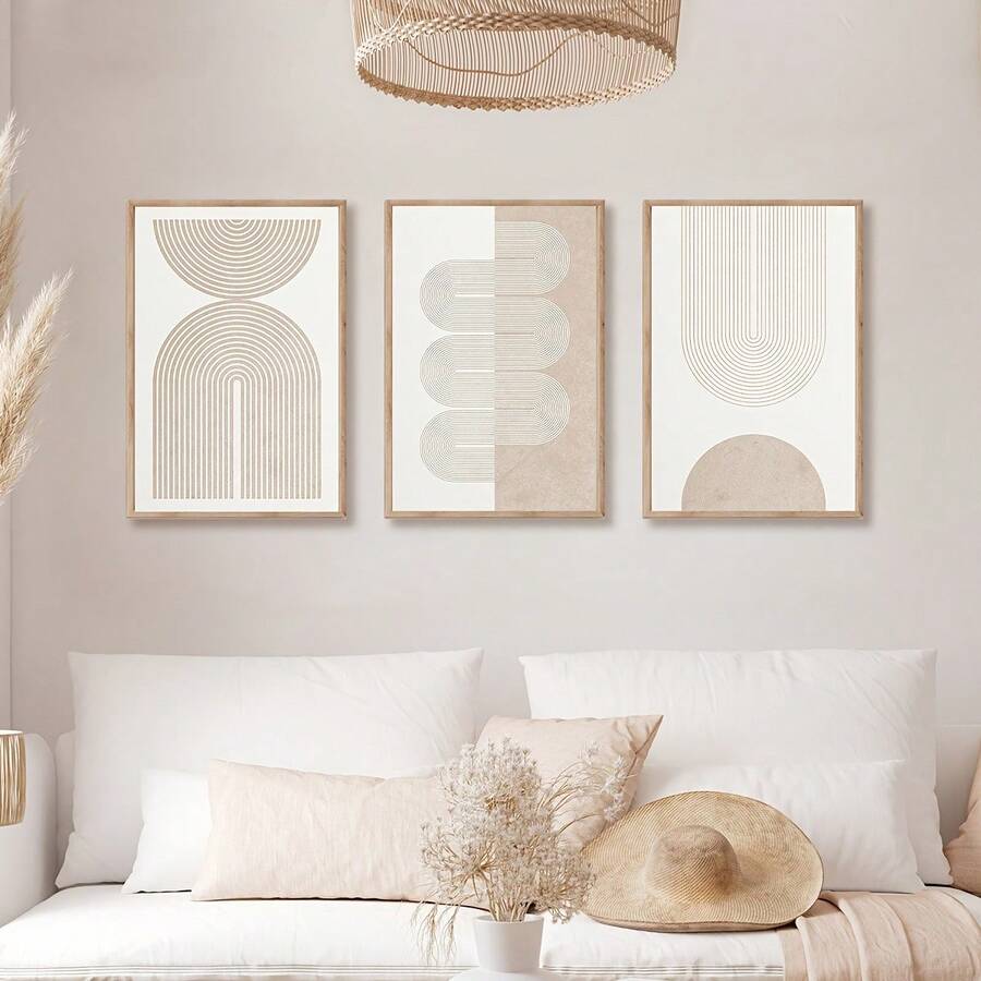 Neutral geometric triptych above a styled bed with pampas grass and a woven wall hat