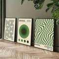 Three green geometric canvas posters leaning beside indoor plants