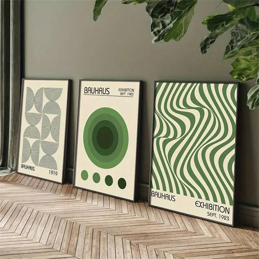 Three green geometric canvas posters leaning beside indoor plants