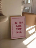 Framed pink quote print reading BETTER LATE THAN UGLY leaning in sunny neutral room