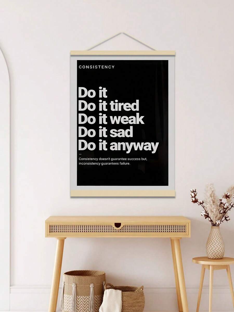 Hanging black consistency poster above light wood console table with baskets and vase