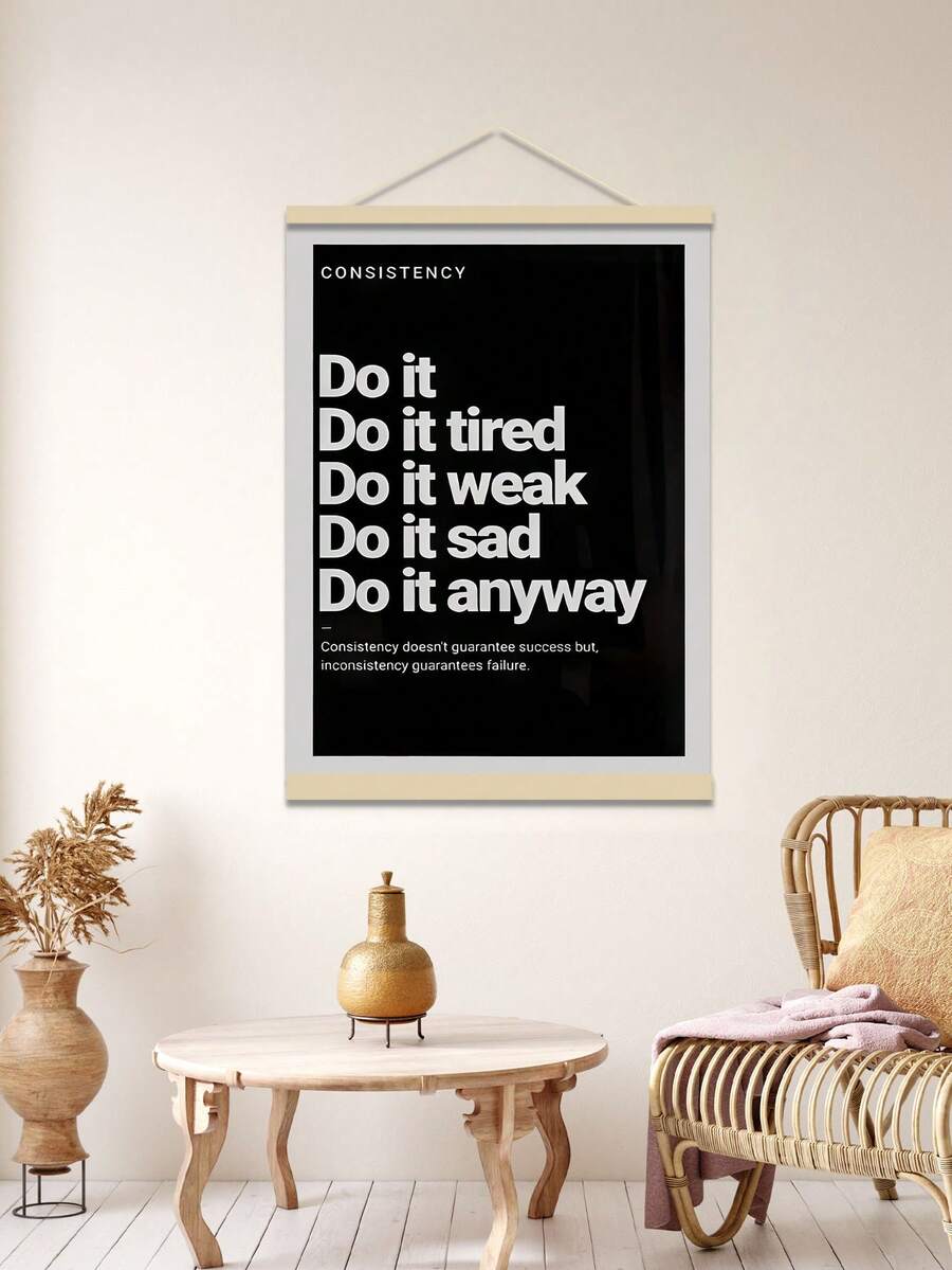 Hanging black consistency poster above round table and rattan chair in beige room
