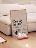 Framed beige Do it for the plot quote poster leaning by white sofa with books