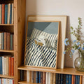 Teddy bear reading print propped in a warm bookshelf nook