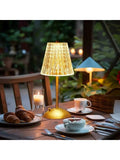 Portable dimmable table lamp with clear faceted shade and gold base.