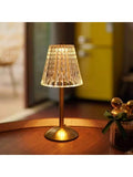 Gold brass cordless lamp shown beside books, candle, plants, and food.