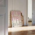 Pink and cream New York skyline artwork against a paneled hallway wall