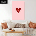 Pink red heart canvas print hanging above white sofa in cozy living room with warm pillows