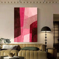 Framed abstract geometric wall art with blush pink and burgundy shapes above an olive sofa