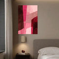 Vertical geometric abstract canvas artwork adding soft pink color to a bedroom wall