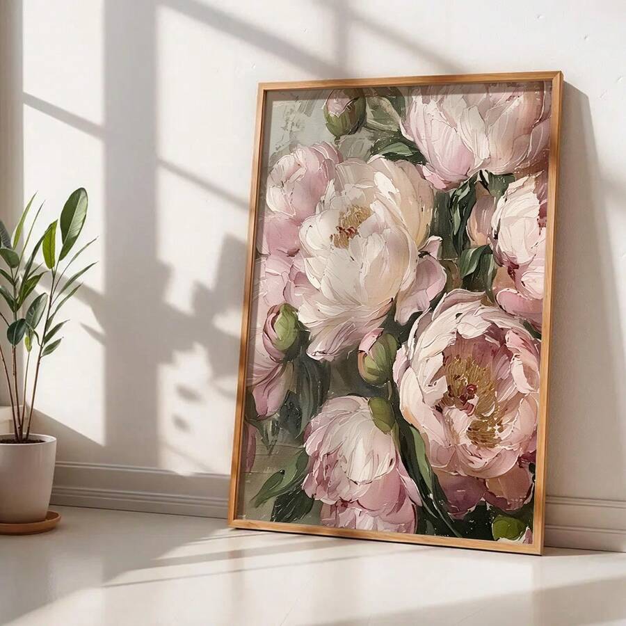 Pink peony floral canvas print in light wood frame leaning on white wall beside potted plant