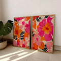Pink and orange botanical poster set leaning beside a monstera plant