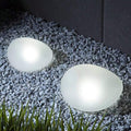 Outdoor pathway lights cool white glow in gravel border with frosted rock shape