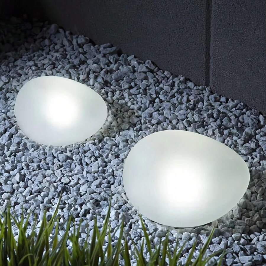 Outdoor pathway lights cool white glow in gravel border with frosted rock shape