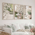 Three spring botanical canvas posters displayed above an airy white living room sofa