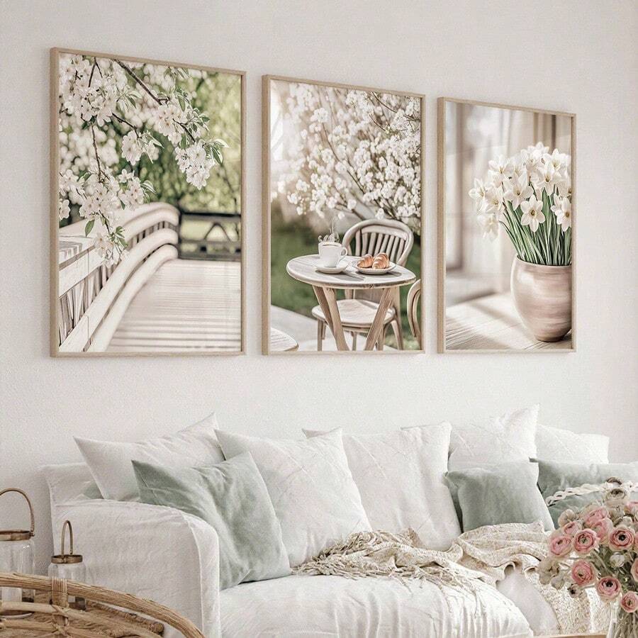 Three spring botanical canvas posters displayed above an airy white living room sofa