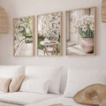 Neutral floral triptych with blossoms and daffodils above a white sectional sofa