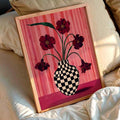 Floral checkered vase canvas print in a wood frame above cream bedroom bedding