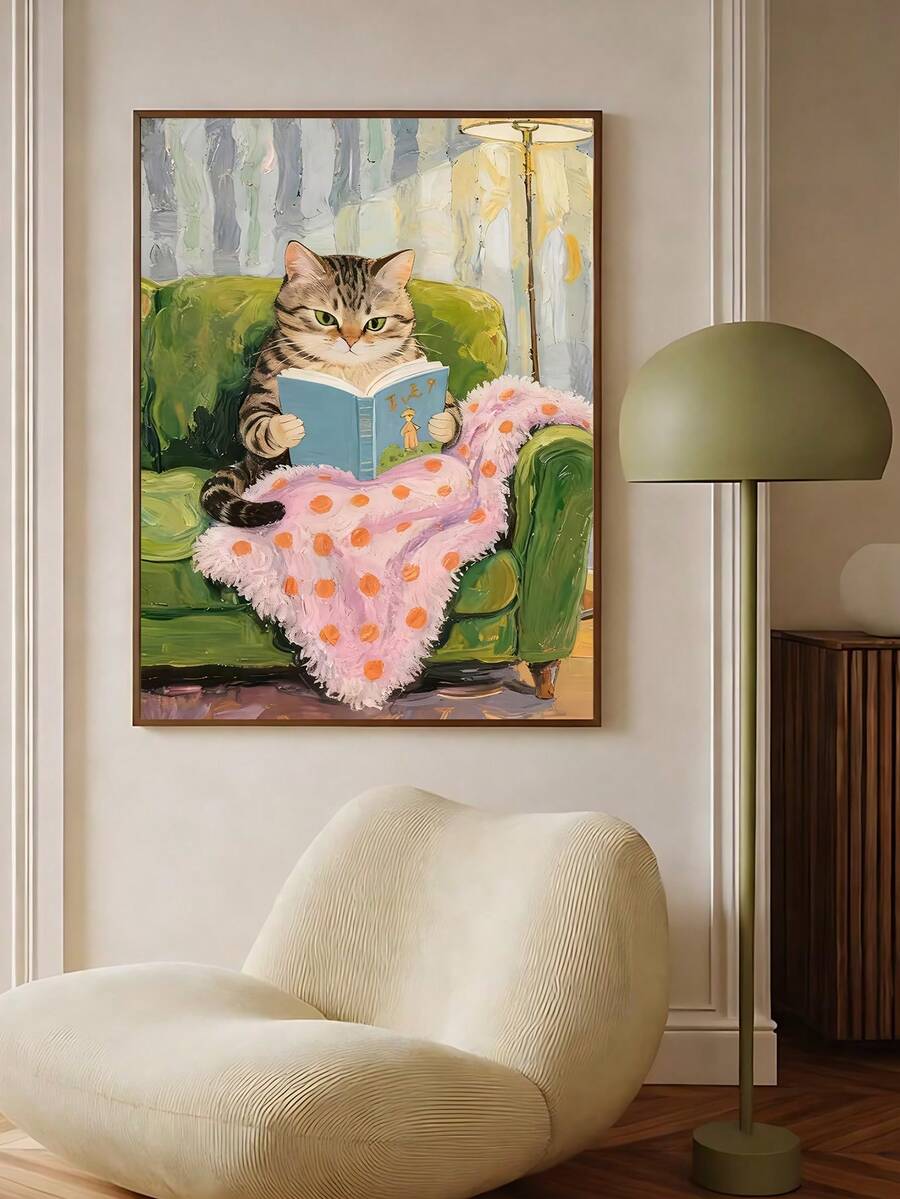Framed cat reading artwork above cream chair beside green floor lamp