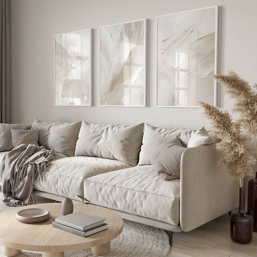 Textured neutral triptych in white frames above sectional sofa