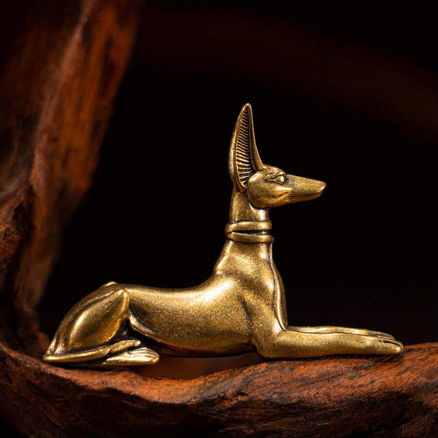 Vintage brass Egyptian jackal statue in lying sphinx pose.