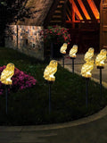 Solar pathway lights shaped like white owls on black garden stakes